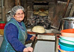 Dona Isabel putting the loaves into the stone oven